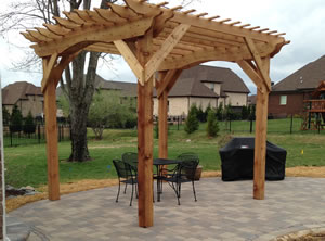 An arbor over a patio with some outdoor furniture