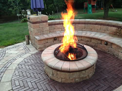 An outdoor fire pit with a spark screen on top and flames coming out